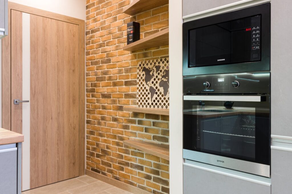 pexels-photo-6969989 Stylish interior kitchen featuring a brick wall and modern appliances.